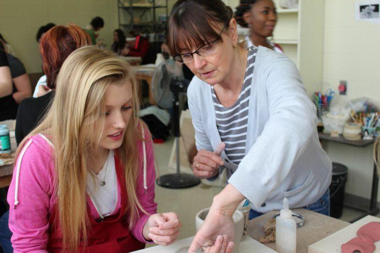 Ceramics student receiving guidance from a teacher.